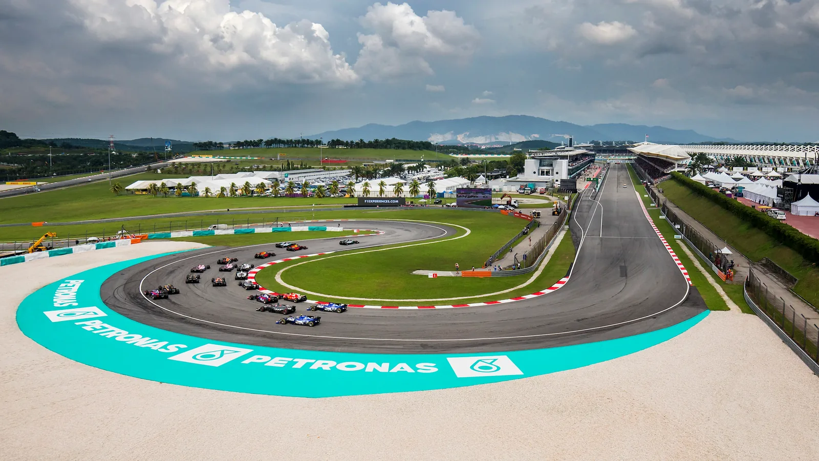 Formula 1 cars negotiate Sepang's final hairpin with the main straight and grandstands alongside