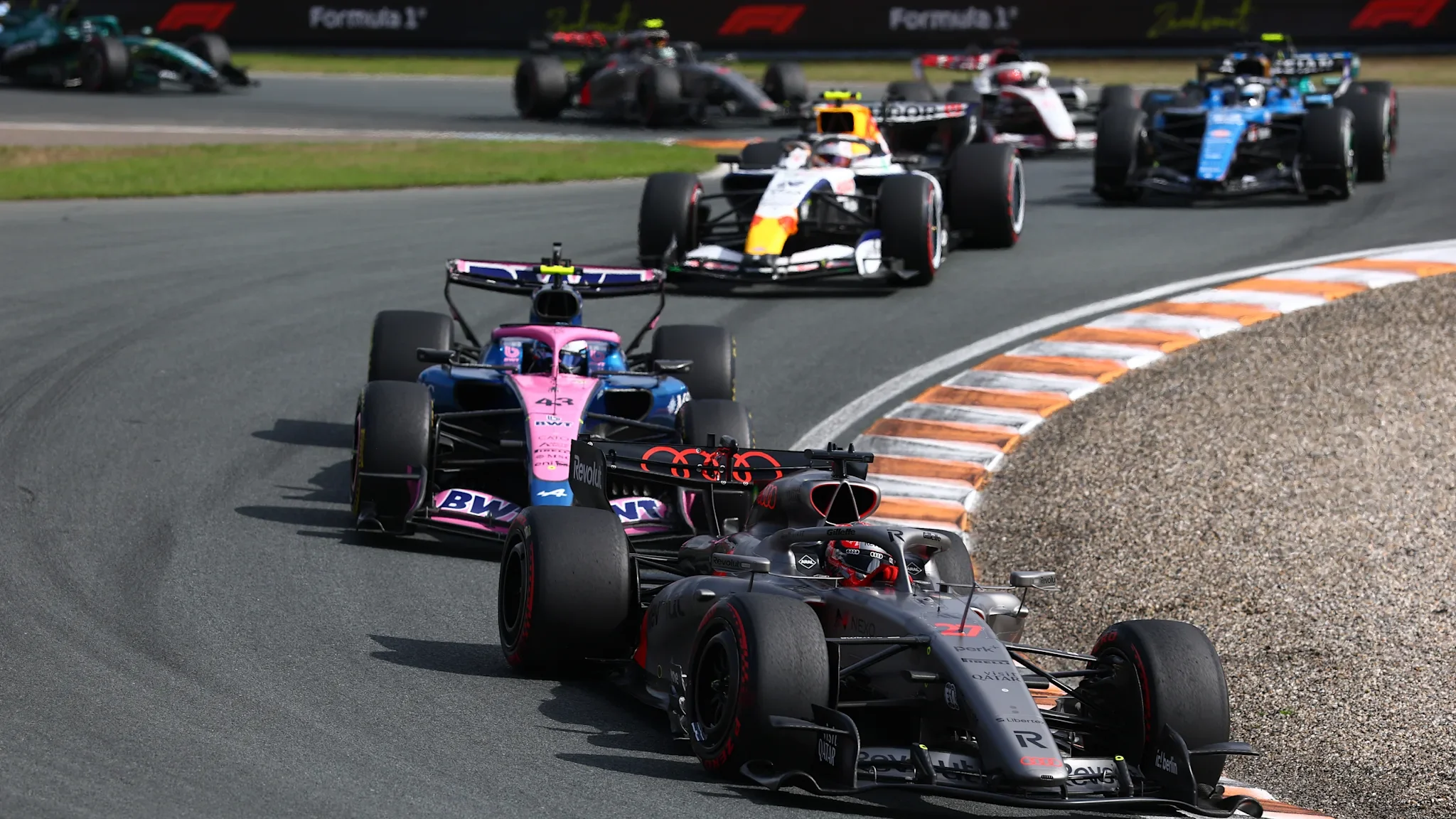 A tightly packed group of Formula 1 cars navigating the banked Zandvoort circuit during the 2026 Dutch Grand Prix