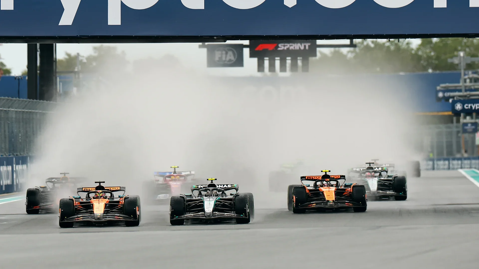 Formula 1 cars racing beneath an F1 Sprint gantry