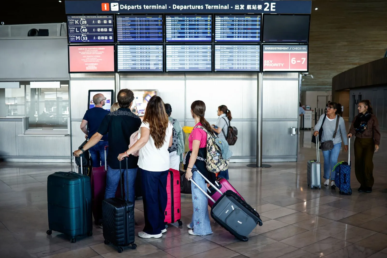 Air travelers with suitcases checking departure information in an airport terminal