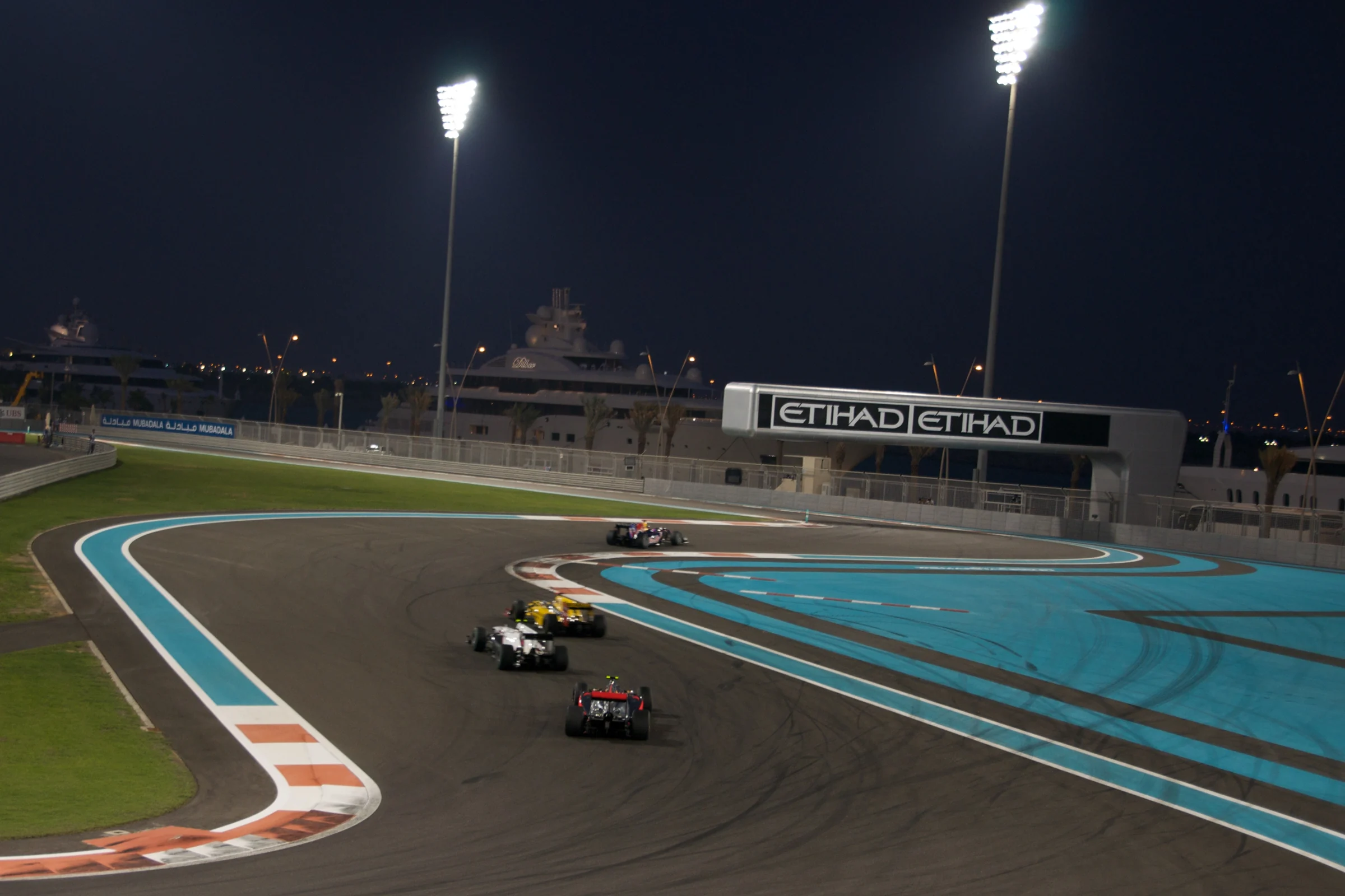 Formula 1 cars racing through Yas Marina Circuit under floodlights