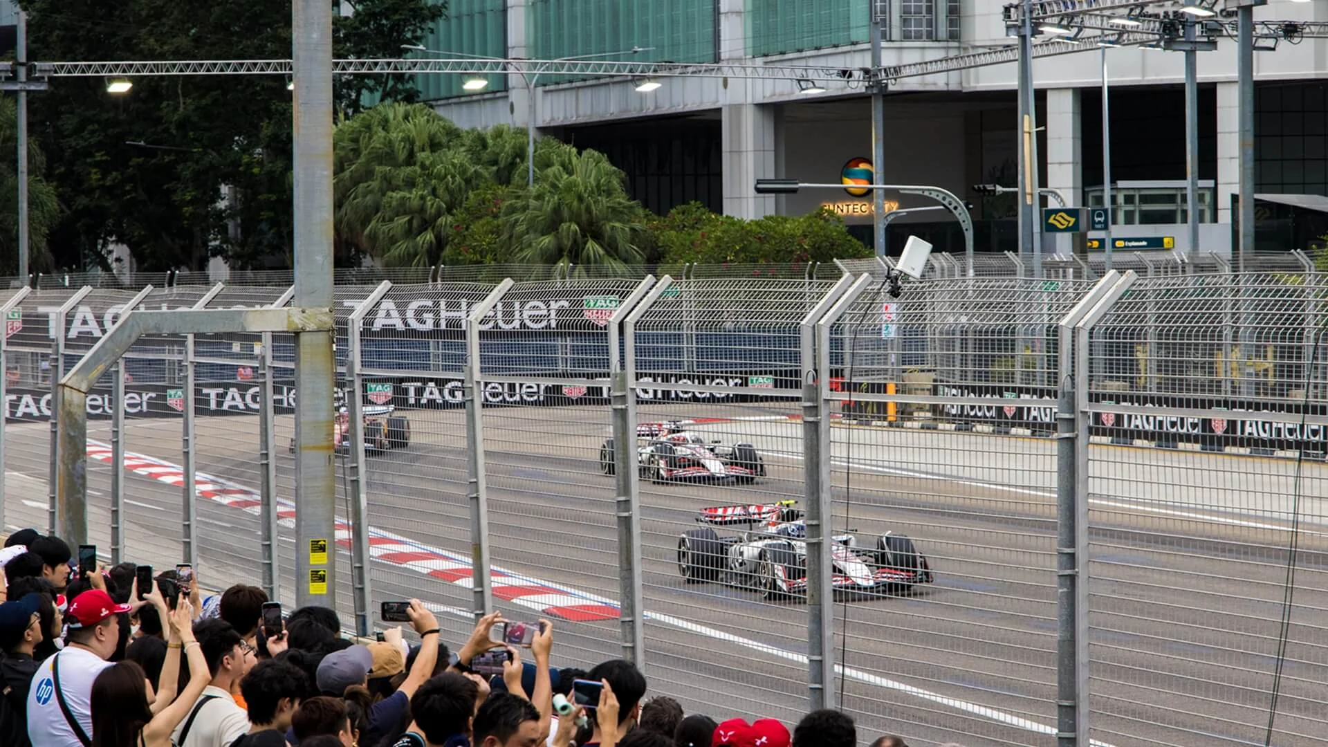 Zone 4 walkabout spectators watching Formula 1 cars through the circuit safety fence in Singapore